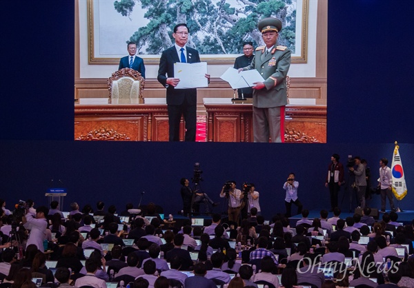 남북정상회담 둘째날인 19일 오전 평양 백화원영빈관에서 문재인 대통령과 김정은 국무위원장이 지켜보는 가운데, 송영무 국방부장관과 노광철 인민무력상이 ‘판문점선언 이행을 위한 군사분야 합의서’에 서명하고 있다. 이 장면이 서울 동대문디자인플라자에 설치된 프레스센터 대형모니터를 통해 생중계되고 있다.