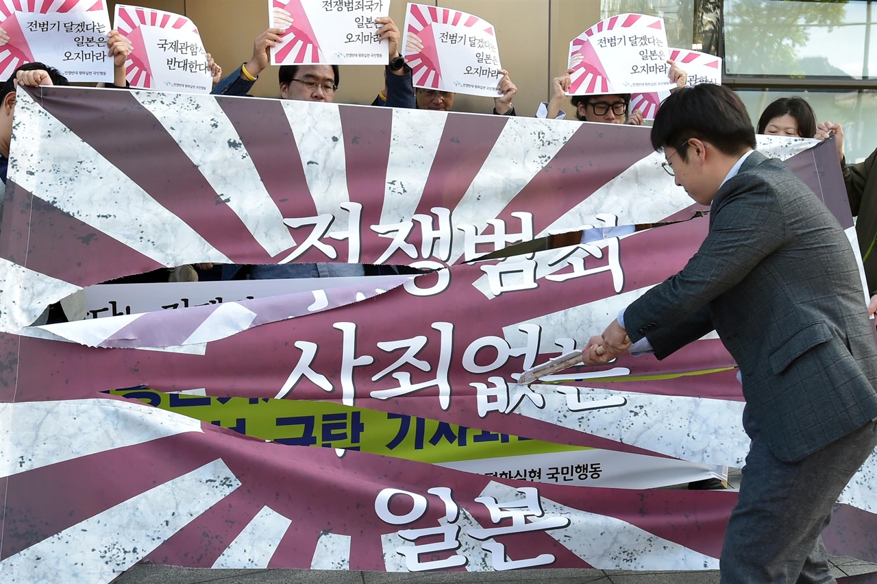  전쟁반대평화실현국민행동 관계자들이 1일 오후 서울 종로구 일본대사관 앞에서 ‘욱일승천기를 단 일본군함의 국제관함식 참석 규탄 기자회견’을 열고 일본의 전범기를 칼로 자르는 퍼포먼스를 펼치고 있다. 2018.10.1