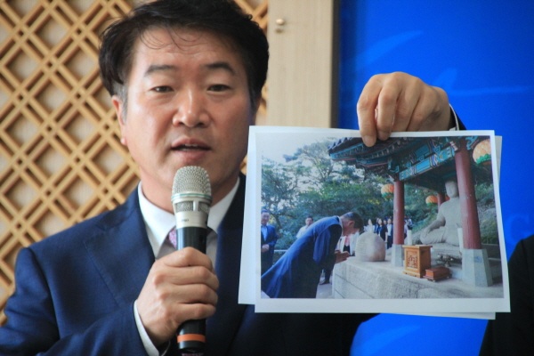 박임관 시민운동본부 학술전문위원장이 기자회견을 하던도중 문재인대통령이 불상을 참배하는 사진을 들어 보이고 있다.