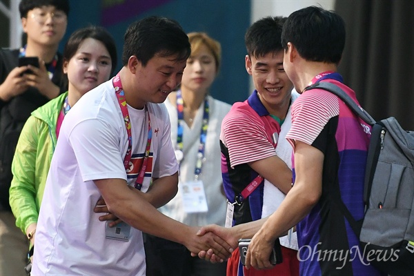  '2018 인도네시아 장애인아시아경기대회' 탁구 남북 단일팀 남측 문창주(오른쪽) 감독과 북측 리철웅(왼쪽) 감독이 5일 오후(현지시간) 인도네시아 자카르타 이컨벤션에서 만나 인사를 나누고 있다. 가운데는 북측 김영록 선수.