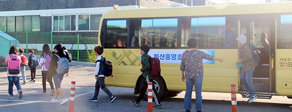 학교에 도착한 학생들이 통학안전요원의 지도아래 버스에서 내리고 있다.