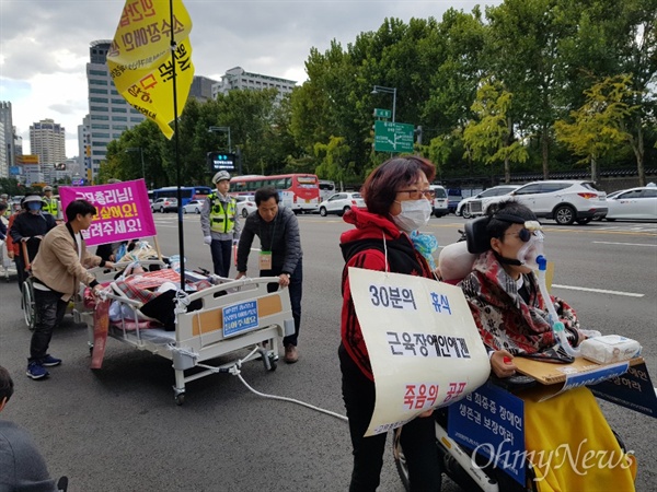 10일 오후 서울 중구 태평로 덕수궁 대한문 앞에서 고위험 희귀난치 근육장애인생존권 보장연대 회원이 침대에 누워 산소호흡기에 의지한 채 행진하고 있다. 