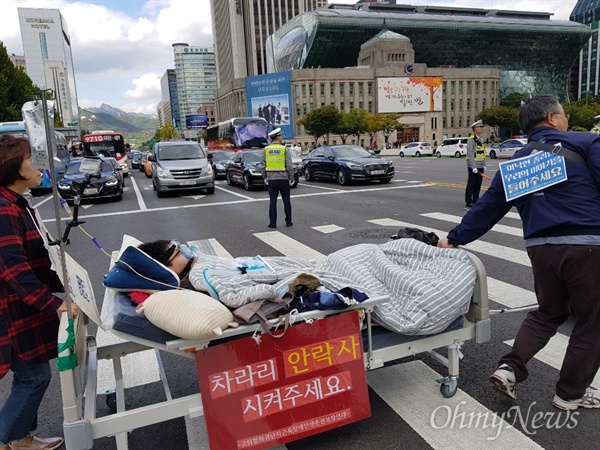 10일 오후 서울 중구 태평로 덕수궁 대한문 앞에서 고위험 희귀난치 근육장애인생존권 보장연대 회원이 침대에 누워 산소호흡기에 의지한 채 행진하고 있다. 