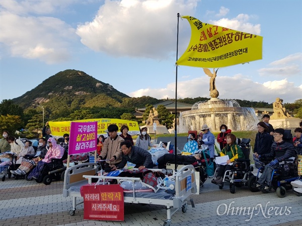  10일 오후 서울 중구 태평로 덕수궁 대한문 앞에서 고위험 희귀난치 근육장애인생존권 보장연대 회원이 침대에 누워 산소호흡기에 의지한 채 행진하고 있다. 