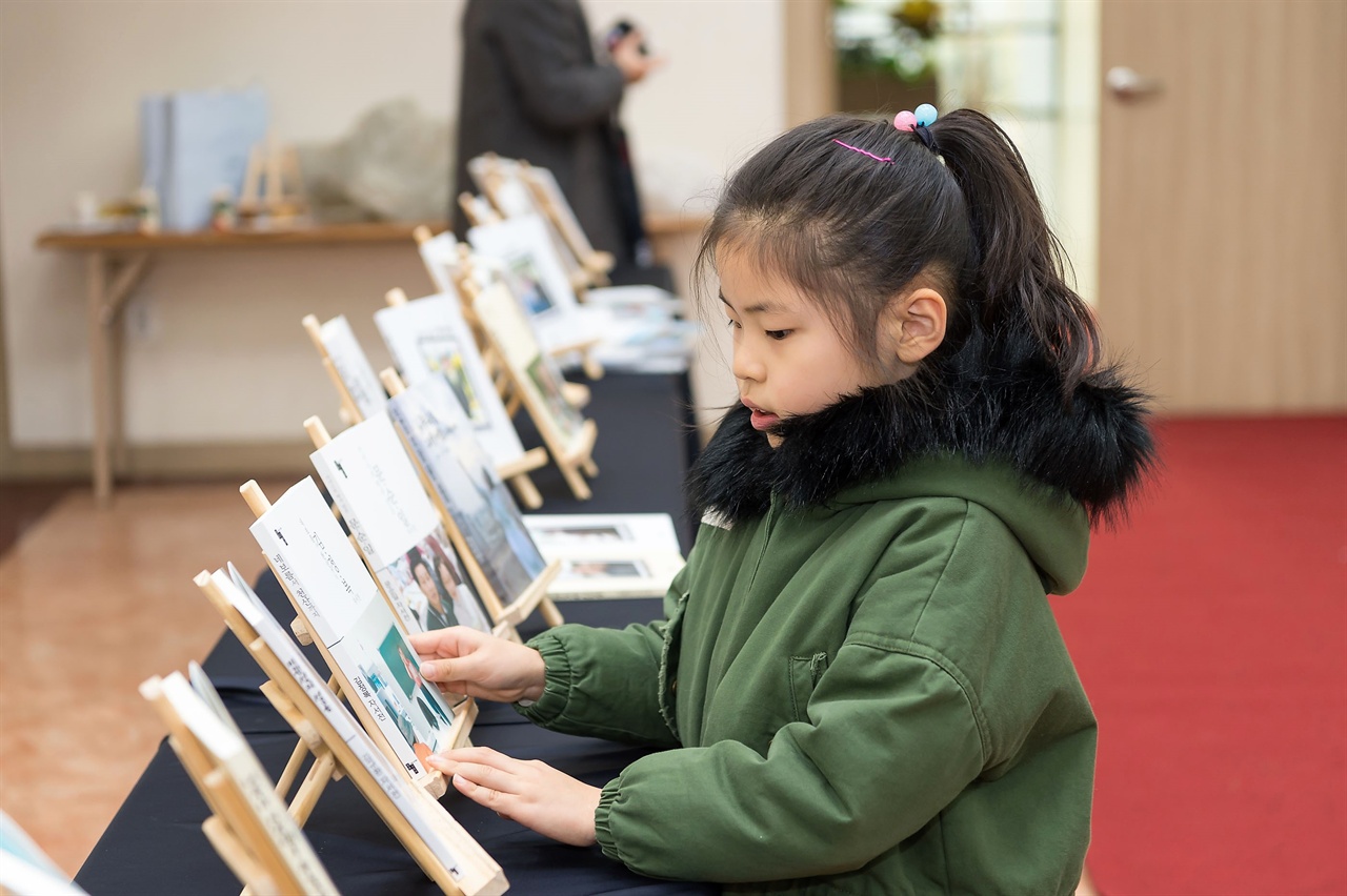 지난 연말 할아버지의 출판기념회에 참석한 어린이가 자서전을 어루만지고 있다.

