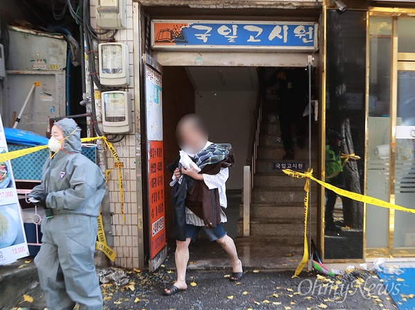 9일 오전 서울 종로구 관수동 한 고시원에서 화재가 발생해 10여명의 사상자가 발생했다. 화재를 피해 탈출한 고시원 생활자가 환자복을 입은 채 불탄 고시원에 들어가 옷가지를 챙겨나오고 있다.