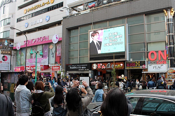 신오쿠보 거리 대형 스크린에 비친 샤이니 고 김종현의 모습을 일본 학생들이 열심히 찍고 있다.