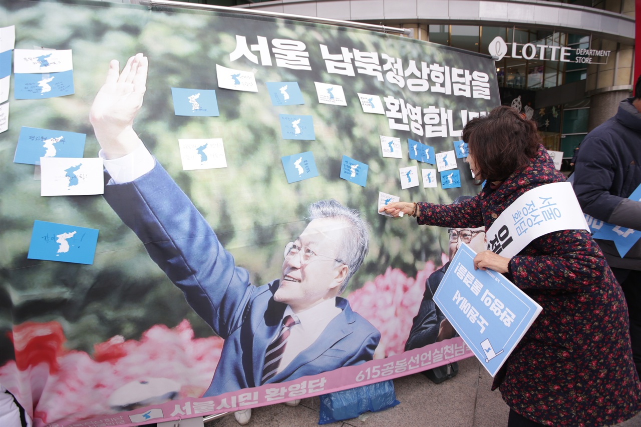 기자회견 참가자 한명이 환영메세지가 담긴 환영엽서를 정상회담 현수막에 부착하고 있다. 