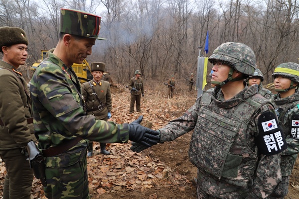 남북이 지난해 11월 22일 오후 공동유해발굴을 위한 지뢰 제거 작업이 진행 중인 강원도 철원 비무장지대(DMZ) 내 화살머리고지에서 전술 도로를 연결한다고 국방부가 밝혔다. 사진은 2018년 11월 도로연결 작업에 참여한 남북인원들이 군사분계선(MDL) 인근에서 인사하는 모습.