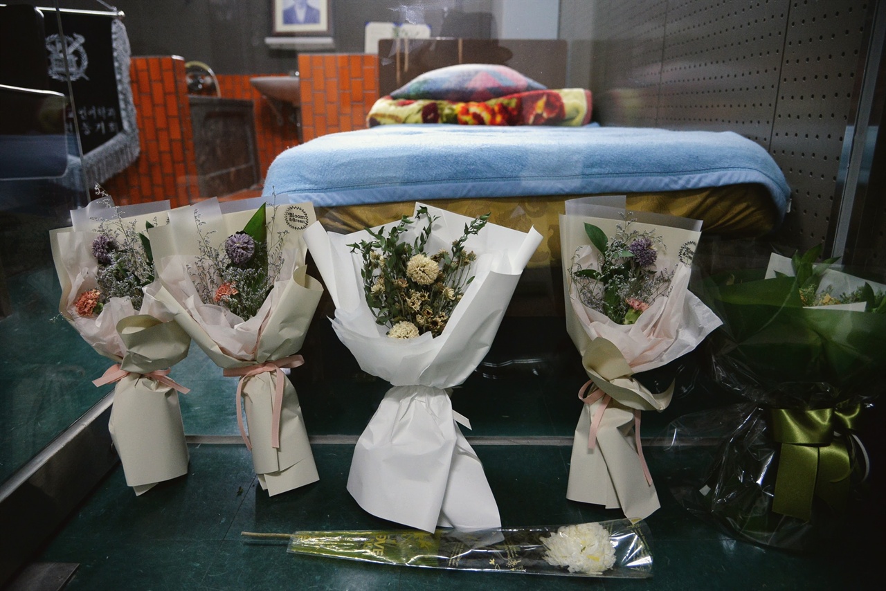 침대 발치에는 시민들이 가져다 놓은 꽃다발이 보인다 