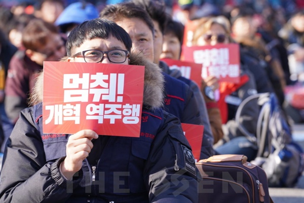  1일 국회 앞에서 민중대회가 열린 가운데 한 참가자가 피켓을 들고 있다. 