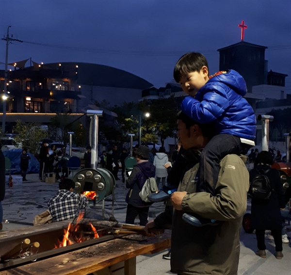 순천문화재 야행의 프로그램 중 하나인 대형화로에서 군밤을 굽는 체험에 부자가 참여하고 있다.  