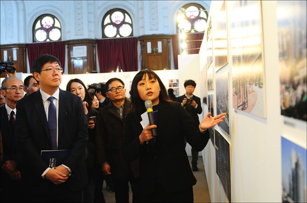 조선신보 로금순 기자가 마이크를 잡고 참가자들에게 직접 자신의 사진을 소개하고 있다.