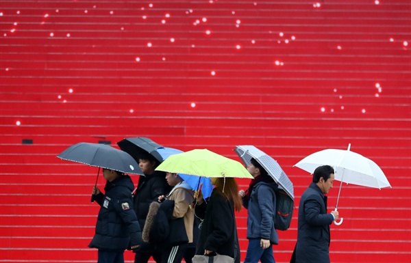 서울을 비롯한 중부지역에 겨울비가 내렸던 지난 3일 오전 서울 광화문 세종문화회관 계단 앞으로 시민들이 길을 지나고 있는 모습. 