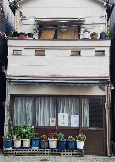 일본 주택가의 2층짜리 가정집 앞에 화분들이 놓여져있다.