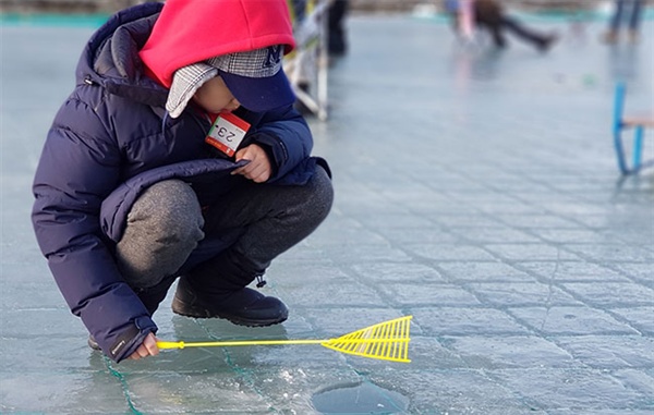2018평창송어축제장에서 어린이 송어낚시 행사에 참가한 한 초등학생이 "언제 송어가 잡힐까" 기대하면서 얼음구멍을 뚫어져라 쳐다보고 있다.