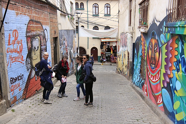여행자들이 사가르나가 거리에서 벽화를 구경하고 있다. 오른쪽 첫번째 화려한 그림은 볼리비아를 대표하는 화가 마마니마마니의  작품이다 