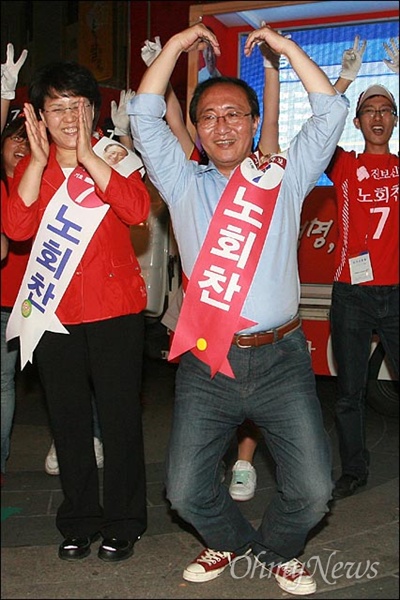 2010년 6월 1일, 노회찬 진보신당 서울시장 후보. 서울 명동입구에서 마지막 선거유세를 하며 선거운동원들과 함께 율동을 하며 하트를 만들고 있는 모습. 