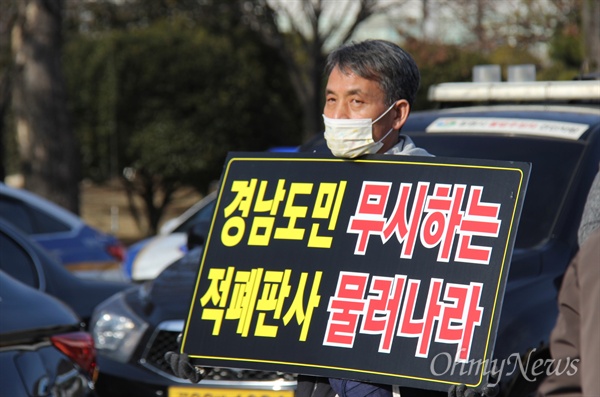 2월 9일 오후 경남도청 정문 앞에서 열린 '제2차 김경수 도지사 불구속 재판 촉구대회"에 한 참석자가 손팻말을 들고 서 있다.