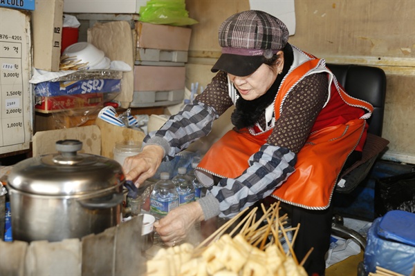 김정순 할머니가 커피를 담은 컵에 물을 따르고 있다. 김 할머니는 여기서 커피와 어묵, 핫도그 등을 팔고 있다.