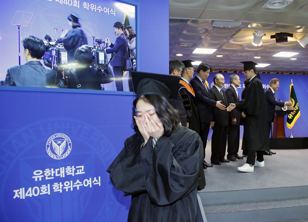 한 졸업생이 부천시 유한대학교에서 열린 졸업식에서 상장을 수상한 뒤 문재인 대통령과 악수 후 단상을 내려가고 있다.