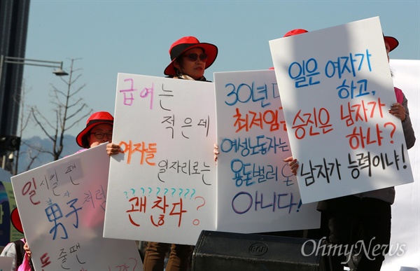 2019년 3월 8일 '3.8 세계여성의 날'을 맞아 서울 광화문광장에서 '성별임금격차 해소를 위한 제 3회 3시 STOP 
 조기 퇴근 시위'가 열렸다. 참가자들이 성차별 사례가 적힌 피켓을 들고 있다.