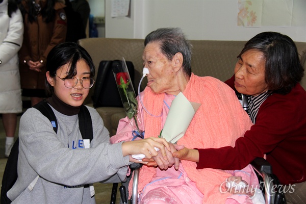  일본군위안부 할머니와 함께하는 마산창원진해시민모임은 3월 13일 오후 마산우리요양병원에서 김양주 할머니 생일잔치를 열었고, 한 여학생이 할머니의 손을 잡고 있다.