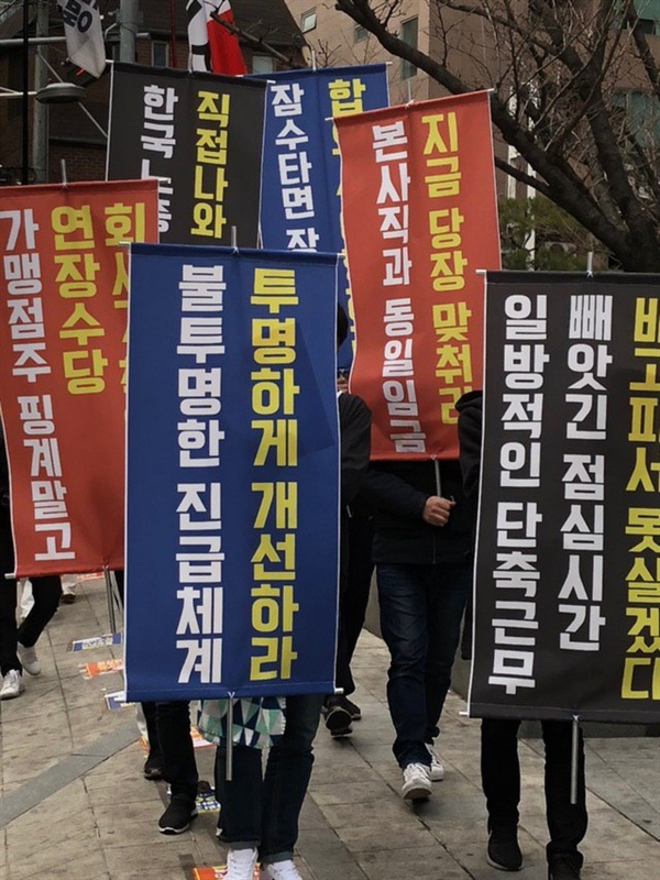 집회를 마친 참가자들이 현수막을 앞세우고 SPC 건물을 돌고 있다. ▲잠수타면 장땡이냐, 합의서 이행하라 ▲일방적인 단축근무, 빼아긴 점심시간, 배고파서 못살겠다 ▲한국노총 핑계말고, 직접나와 대화하라 ▲가맹점주 핑계말고, 연장수당 회사가 책임져라 ▲불투명한 진급체계, 투명하게 개선하라 