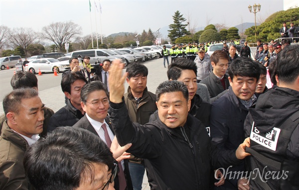  3월 15일 오후 '대우조선해양 매각반대, 지역경제살리기 경남대책위원회'가 경남도청 현관 앞에서 대화를 요구하며 손팻말을 들고 서 있는 가운데, 정승일 산업통상자원부 차관이 간담회 참석을 위해 차량에서 내려 경찰의 보호를 받으며 경남도청 안으로 들어가고 있다.