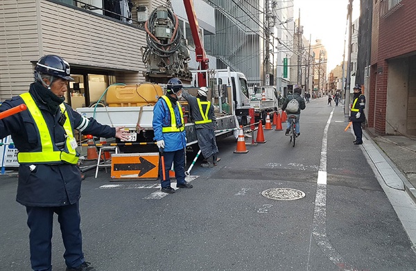 도쿄의 한 건물 공사장 앞에서 행인들을 안내하는 안전 요원들.
