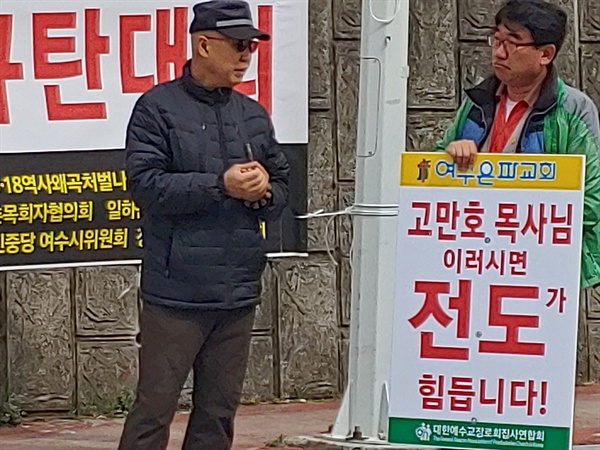  한 집회참가자가 든 '고만호 목사님 이러시면 전도가 힘듭니다'라는 피켓을 지나가는 시민이 바라보고 있다