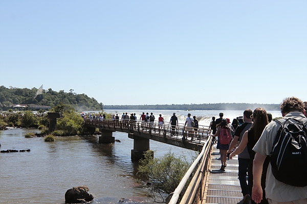 이구아수폭포로 이어지는 다리를 걸어가는 관광객들 