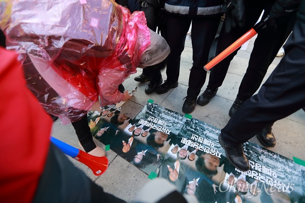 '박근혜 석방' 요구 대한애국당 집회에 참석했던 한 참가자가 박근혜 전 대통령 사진이 실린 집회포스터가 사람들 발에 밟힌다며 포스터를 뜯어내고 있다.