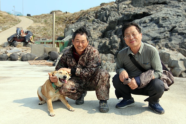 김영태 이장(왼쪽)과 목포대학교 도서문화연구원 이재언씨 모습. 이웃집 개와 혈투를 벌이고 힘들어하는 개를 주인인 김영태씨가  쓰다듬어 주고 있다