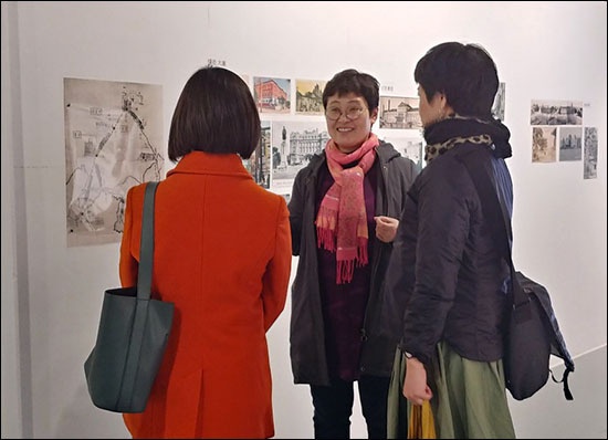 이번 전시를 기획한 도다 이쿠코(관동갤러리 관장) 씨가 일본인들에게 사진 설명을 하고 있다.(가운데)