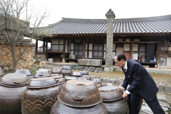 박경중 어르신이 장독 항아리의 뚜껑을 열고 있다. 집안의 장독대가 안채의 뒤안을 배경으로 자리하고 있다. 그 앞에는 다른 굴뚝과 달리, 높이 세워 바람의 영향을 피한 굴뚝이 눈길을 끈다.