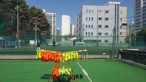   풋살조끼가 널린 건조대 위쪽으로 경기에 앞서 몸푸는 센터 아이들과 선생님들