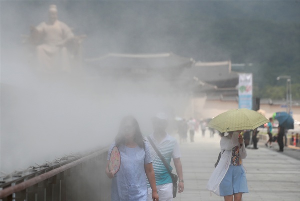 서울 낮기온이 30도를 웃돌며 더운 날씨를 보인 2018년 7월 4일 서울 세종대로 광화문광장에 설치된 '쿨링포그(Cooling Fog)' 주변으로 시민들이 부채와 양산을 들고 오가고 있다.
