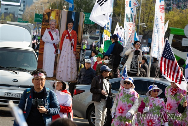 박근혜 전 대통령과 엘리자베스 영국 여왕이 함께 있는 사진을 든 대한애국당원들이 13일 오후 서울 세종로 네거리에서 '박근혜 석방'을 요구하며 행진하고 있다.