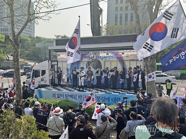 홍문종 자유한국당 의원이 지난 24일 오후 서울중앙지검 앞에서 진행된 대한애국당 집회에 참석해 박근혜 전 대통령의 석방을 요구했다. 연단 가운데 회색 양복을 입은 인물이 홍 의원이다. 