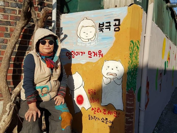 소중애 작가가 자신의 <북극곰 엉덩이가 뜨거워!>라는 작품을 그린 벽화 앞에 앉았다