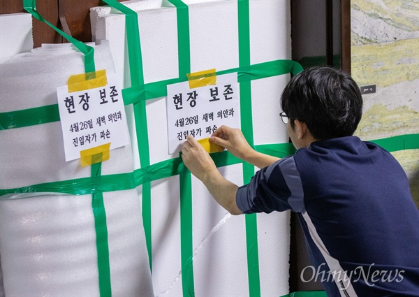 자유한국당 당직자들이 26일 오전 서울 국회 의안과 앞에서 여야4당의 패스트트랙 지정 강행 저지를 위해 농성을 벌이며 부숴 진 입구에 '현장보존'이 적힌 종이를 부착하고 있다. 