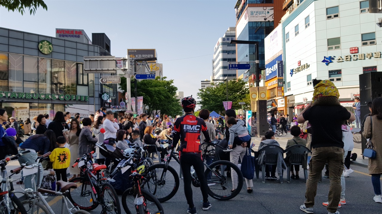미세먼지를 줄이기 위한 대책으로 자전거를 타고 나온 시민들이 거리에서 공연을 지켜보고 있다