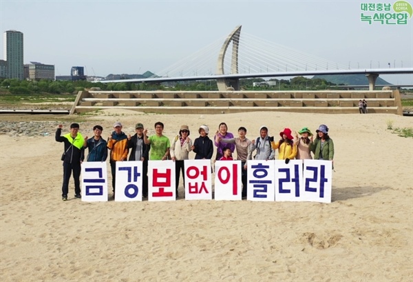 세종보 수문개방 후 모래톱이 형성된 곳에서 대전충남녹색연합 회원들이 금강 보 철거를 염원하는 피켓 현수막을 하고 있다.