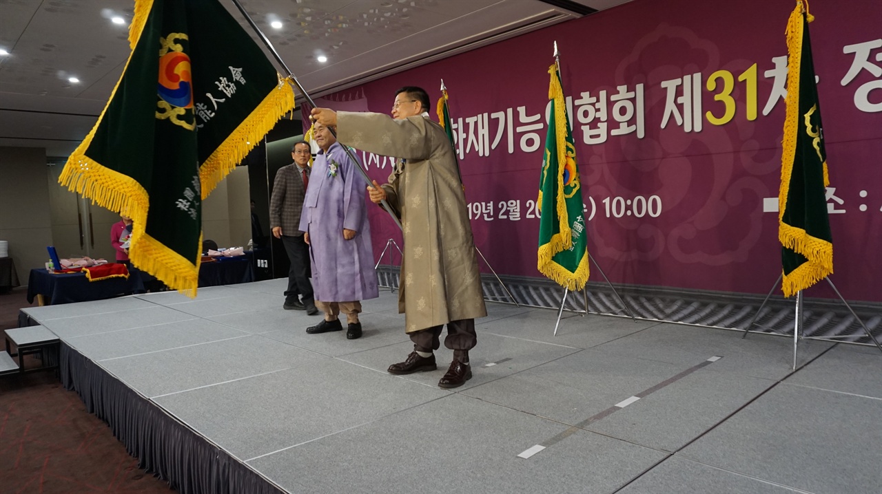2019년 2월 20일, 이광복 신임이사장(가운데)이 전 이사장으로부터 협회깃발을 전달받아 흔들고 있다.