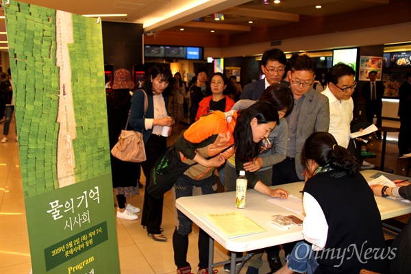 5월 2일 저녁 롯데시네마 창원점에서 열린 영화 <물의 기억> 시사회에 참가한 관람객들이 입장권을 받고 있다.