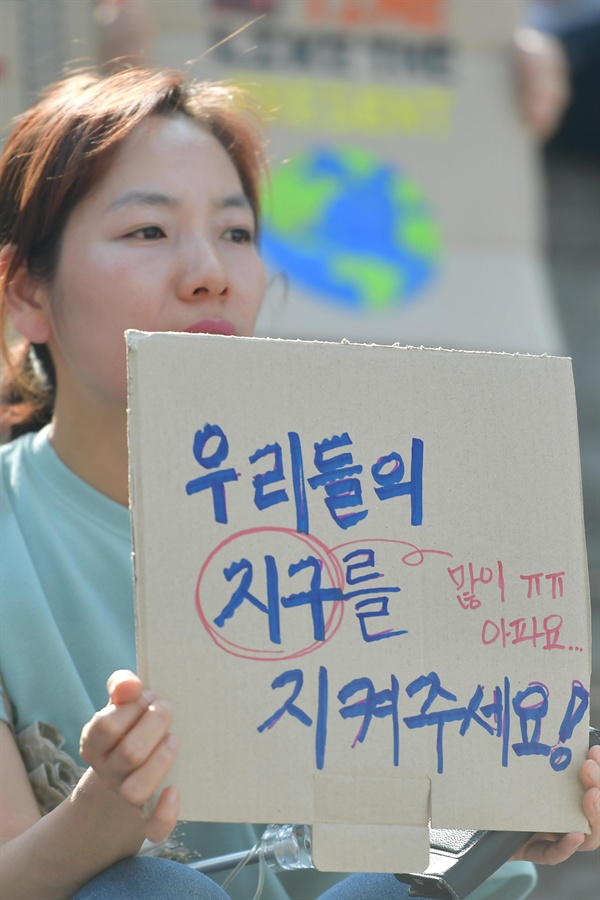  24일 오후 서울 종로구 세종문화회관 중앙계단에서 열린 '524청소년기후변화 해결 촉구 공동행동'에 참여한 학부모가 "우리들의 지구를 지켜주세요!"라고 써진 손팻말을 들고 있다. 2019.05.24