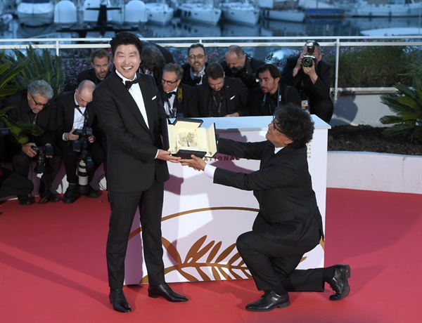 영화 <기생충>의 봉준호 감독과 송강호가 황금종려상 수상 후 포토콜 행사에서 포즈를 취하고 있다.