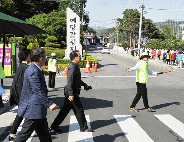  보건소 직원들은 방문객들의 안전을 위해 차량을 막아 길을 내주고 있다.