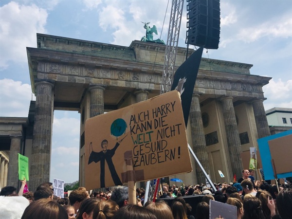 브라덴부르크문 앞에서 열린 환경 시위에서 참가자가 직접 만든 플래카드를 들고 있다. 플래카드에는 "해리포터 또한 세계가 다시 건강하도록 마법을 부릴 수 없다"라고 쓰여 있다. 